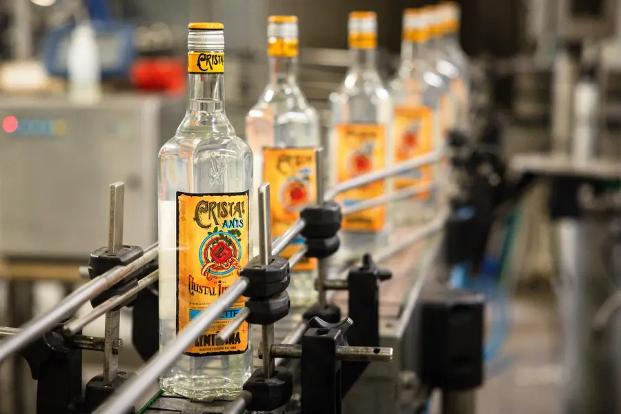 Alignement de bouteilles d'anisette Cristal Anis sur la chaîne d'embouteillage de l'usine Cristal Limiñana à Marseille.