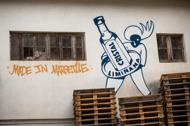 Façade de l'usine Cristal Limiñana à Marseille avec une peinture murale représentant le logo de la marque et l'inscription Made in Marseille.