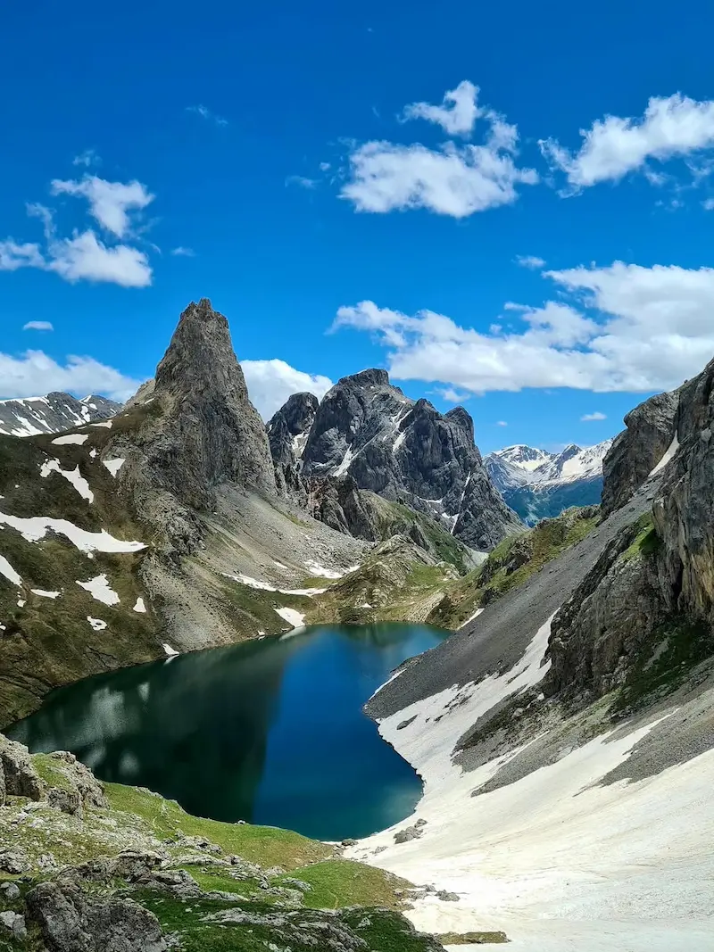 Grand Lac du Lauzet entouré de névés et de sommets rocheux dans les Alpes du sud